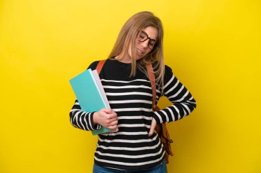 Sarı arka planda izole edilmiş genç bir bayan, çabaladığı için sırt ağrısı çekiyor.