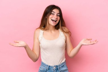 Genç beyaz kadın pembe arka planda izole edilmiş, şok olmuş yüz ifadesi var.