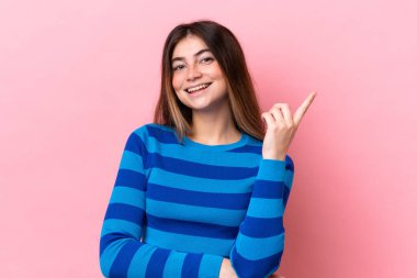 Pembe arka planda izole edilmiş beyaz bir kadın harika bir fikre işaret ediyor.