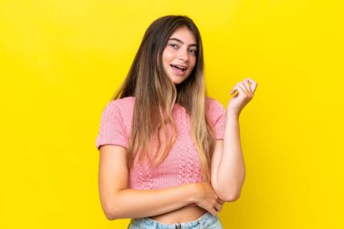 Sarı arka planda izole edilmiş genç beyaz kadın gülüyor.