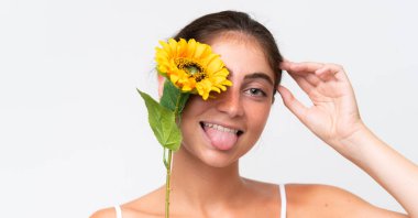 Young Pretty caucasian woman isolated on white background holding a sunflower while smiling. Close up portrait