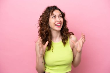 Pembe arka planda yalıtılmış beyaz bir kadın. Şaşırtıcı bir yüz ifadesi var.