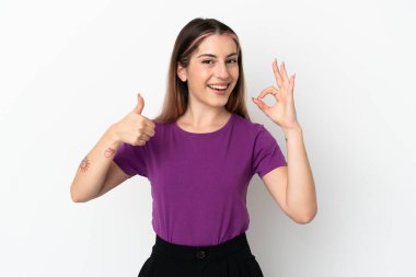 Beyaz arka planda izole edilmiş genç beyaz bir kadın tamam işareti ve baş parmak hareketi gösteriyor.