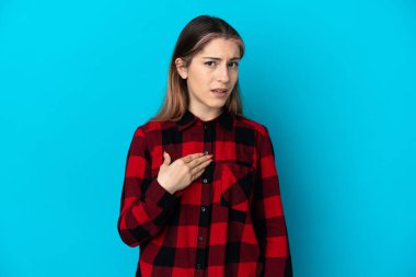 Mavi arka planda izole edilmiş genç beyaz kadın kendini işaret ediyor.