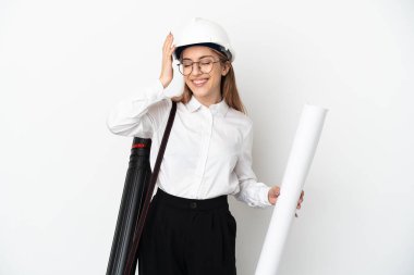 Young architect woman with helmet and holding blueprints isolated on white background smiling a lot