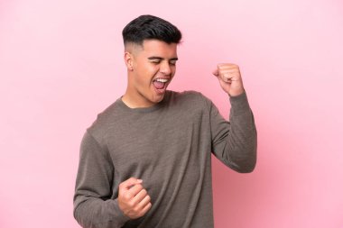 Pembe arka planda izole edilmiş beyaz yakışıklı bir adam zaferi kutluyor.