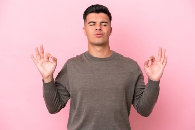 Zen pozisyonunda pembe arka planda izole edilmiş beyaz yakışıklı bir adam.