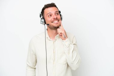 Tele pazarlamacı, beyaz arka planda izole edilmiş bir kulaklıkla çalışan beyaz bir adam yukarı bakarken bir fikir düşünüyor.