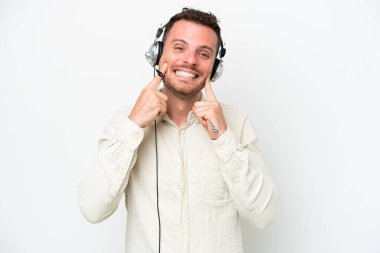 Tele pazarlamacı beyaz bir kulaklıkla çalışan beyaz bir adam mutlu ve hoş bir ifadeyle gülümsüyor.