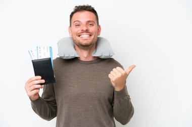 Young caucasian man holding a passport isolated on white background pointing to the side to present a product