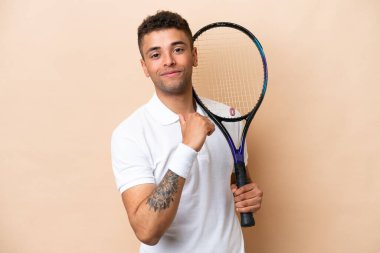 Genç Brezilyalı yakışıklı tenisçi bej arka planda soyutlanmış gururlu ve kendini beğenmiş.