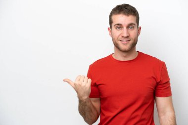 Beyaz arka planda izole edilmiş genç beyaz bir adam bir ürün sunmak için kenarı işaret ediyor.