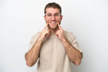 Beyaz arka planda izole edilmiş genç beyaz bir adam mutlu ve hoş bir ifadeyle gülümsüyor.