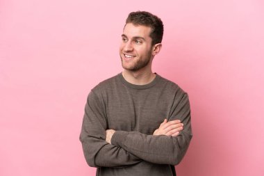 Pembe arka planda izole edilmiş genç beyaz adam mutlu ve gülümsüyor.