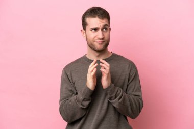 Pembe arka planda izole edilmiş genç beyaz bir adam bir şeyler planlıyor.