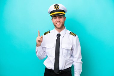 Kafkasyalı uçak pilotu mavi arka planda izole edildi ve en iyinin işareti olarak parmağını kaldırdı.