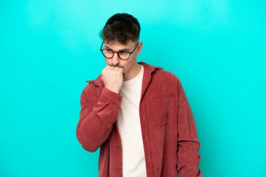 Kafkasyalı yakışıklı genç adam mavi arka planda izole edilmiş şüpheleri var.