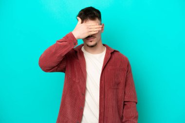 Beyaz tenli yakışıklı bir adam mavi arka planda tek başına, gözleri elleriyle kapatıyor. Bir şey görmek istemiyorum.