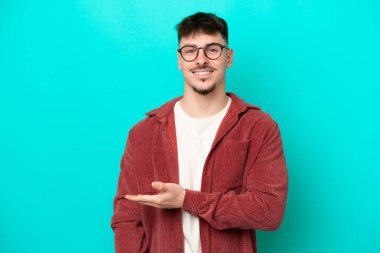 Beyaz tenli yakışıklı adam mavi arka planda izole edilmiş bir şekilde bir fikir sunuyor.