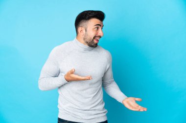 Tarafsız mavi arka plan üzerinde beyaz bir adam sürpriz bir ifadeyle bakarken