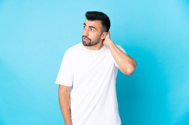 İzole edilmiş mavi arka planı olan beyaz bir adam bir fikir düşünüyor.