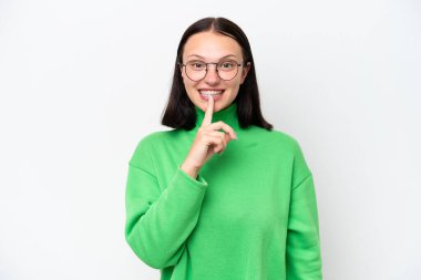 Beyaz arka planda izole edilmiş beyaz bir kadın sessiz bir jest işareti gösteriyor. Parmağını ağzına sokuyor.