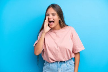 Mavi arka planda izole edilmiş genç beyaz kadın ağzı sonuna kadar açık bağırıyor.