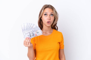 Beyaz arka planda dolarları tutan genç bir Rus kızı şaşırmış bir ifadeyle yukarı bakıyor.