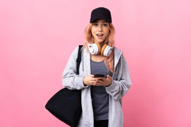 Spor çantalı genç bir bayan izole bir arka planda şaşırdı ve bir mesaj gönderiyor.