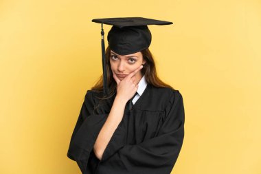 Genç üniversite mezunu, sarı arka planda izole edilmiş.