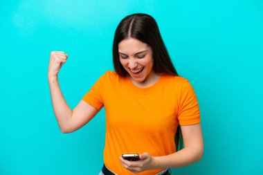 Mavi arka planda izole genç beyaz kadın şaşırdı ve bir mesaj gönderiyor.