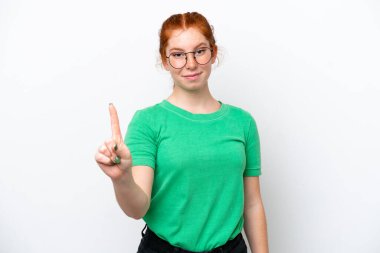 Beyaz arka planda izole edilmiş genç bir kadın parmağını kaldırıyor ve gösteriyor.