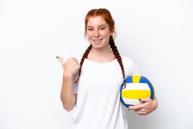 Beyaz arka planda izole edilmiş voleybol oynayan beyaz tenli genç beyaz kadın bir ürünü sunmak için kenarı işaret ediyor.