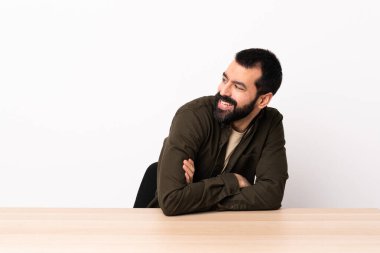 Masada sakallı beyaz bir adam yan tarafa bakıyor ve gülümsüyor..