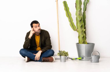 Bahçıvan içeride yerde oturmuş bir fikir düşünüyor.