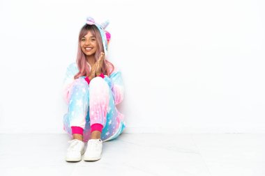 Tek boynuzlu at pijaması giyen genç bir ırk kadını beyaz arka planda izole bir şekilde oturmuş konferansta sunumdan sonra alkışlıyor.