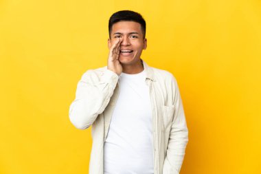Genç Ekvadorlu, sarı arka planda izole edilmiş ağzı açık bağırıyor.
