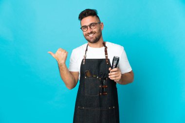 Önlüklü berber bir ürün sunmak için kenarı işaret ediyor.