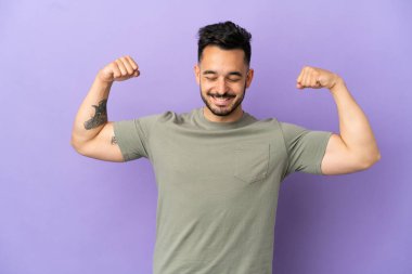Mor arka planda izole genç beyaz adam güçlü bir jest yapıyor.