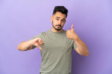 Mor arka planda izole edilmiş beyaz bir adam iyiye-kötüye işaret yapıyor. Evet ya da hayır arasında kararsız