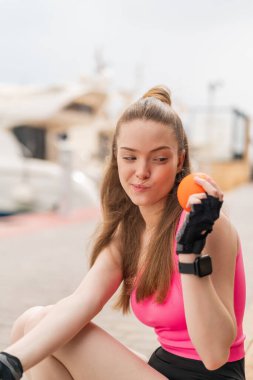 Açık havada elinde portakal tutan genç ve güzel bir kız.