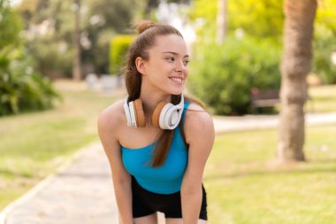 Açık havada genç ve güzel bir kız spor bir elbise giyiyor.