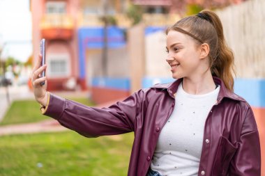 Dışarıda cep telefonu kullanan güzel bir kız. Mutlu bir ifadeyle.