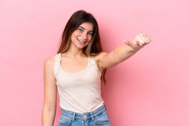 Pembe arka planda izole edilmiş beyaz bir kadın baş parmak hareketi yapıyor.