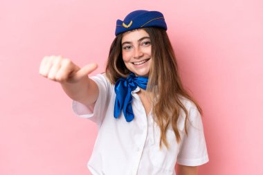 Airplane stewardess caucasian woman isolated on pink background giving a thumbs up gesture