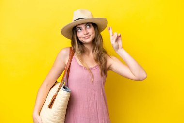 Sarı arka planda izole edilmiş plaj çantası tutan beyaz bir kadın.