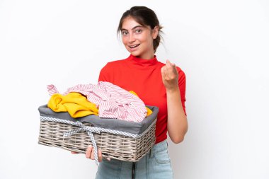 Beyaz arka planda izole edilmiş çamaşır sepetini tutan beyaz bir kadın mutlu bir ifadeyle önü işaret ediyor.