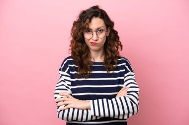 Pembe arka planda izole edilmiş genç beyaz kadın üzgün hissediyor.