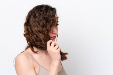 Beyaz arka planda izole edilmiş genç beyaz kadın saçlarına dokunuyor. Portreyi kapat