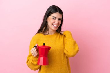 Pembe arka planda kahve makinesini tutan genç İtalyan kadın gülüyor.